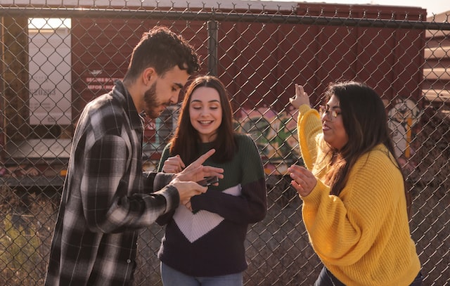 Three teenagers looking at a phone excitedly